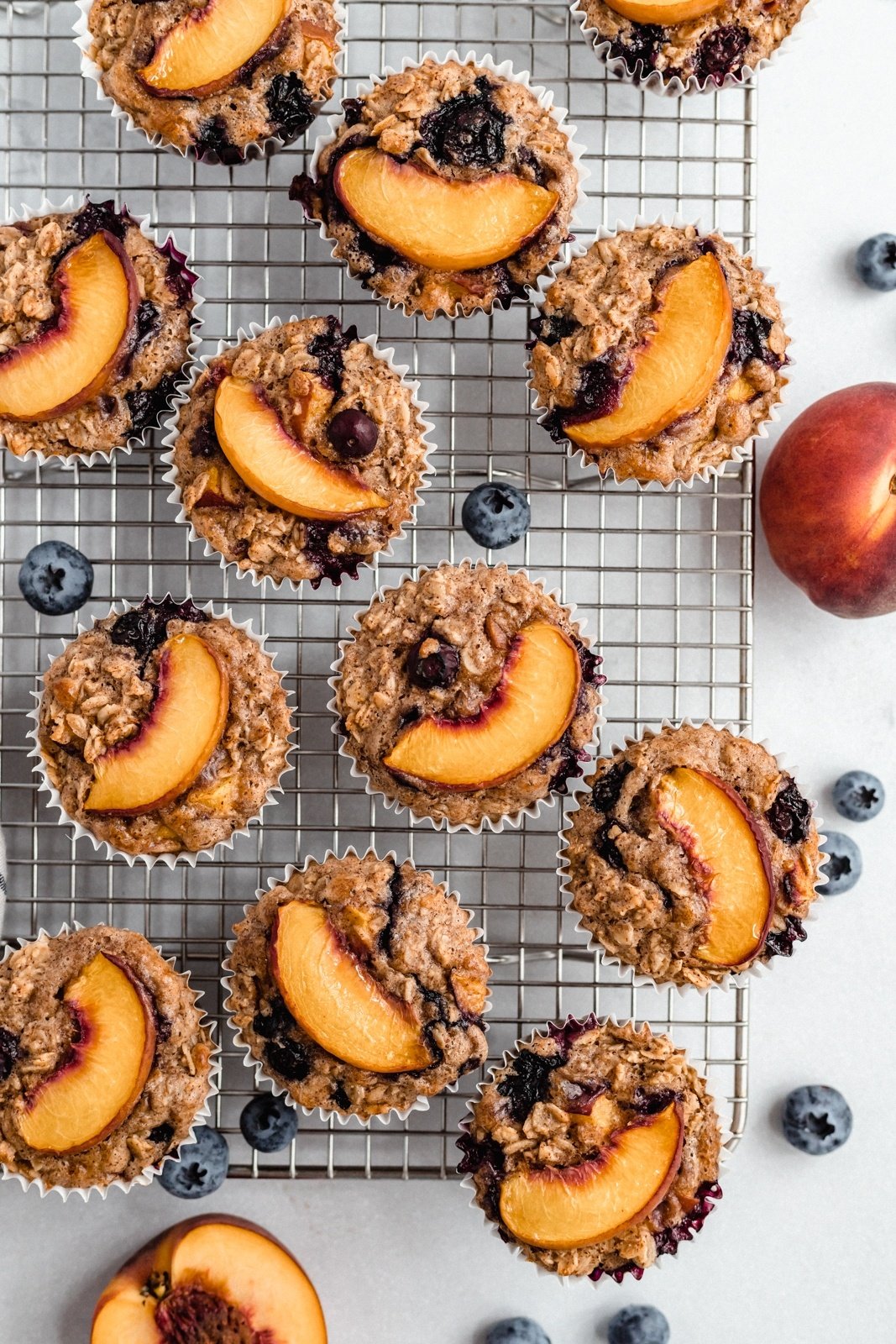 blueberry baked oatmeal cups topped with peach slices on a wire rack