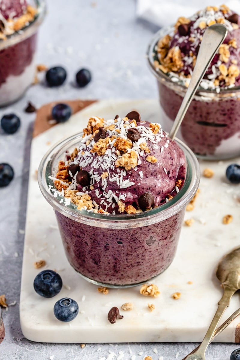 blueberry banana nice cream in a bowl topped with chocolate chips and granola