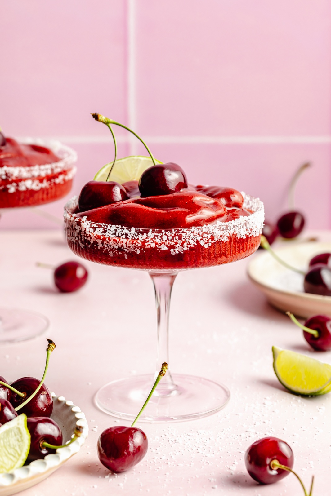 frozen cherry margarita in a glass topped with fresh cherries