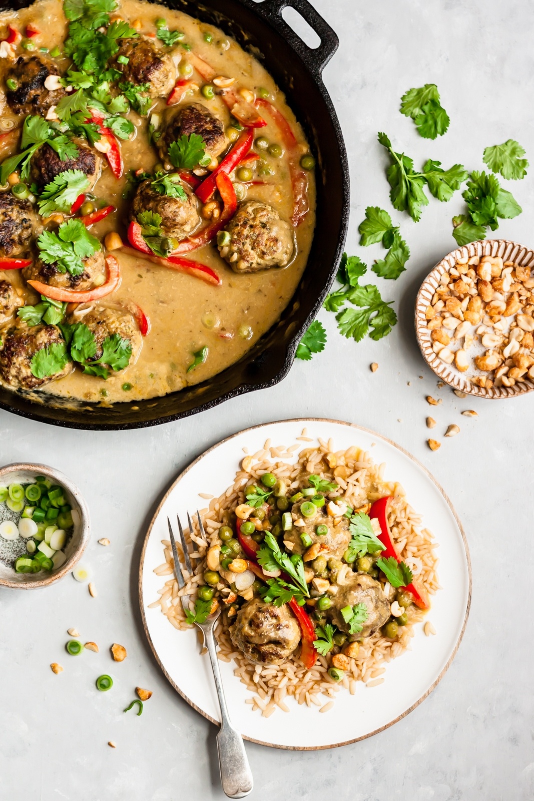 cilantro chicken meatballs in mango coconut sauce on both a skillet and plate with rice