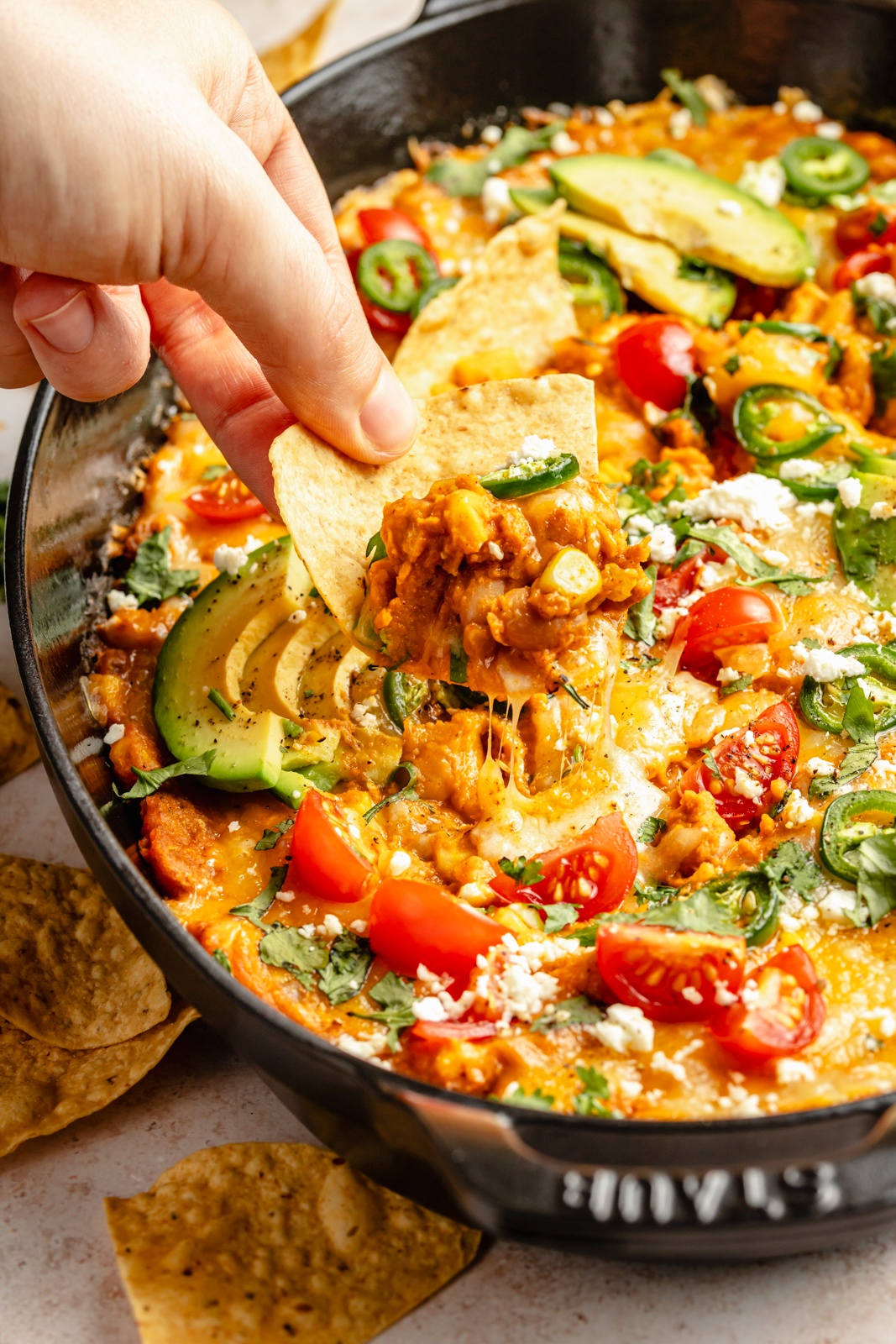 scooping southwest bean dip out of a skillet with a tortilla chip