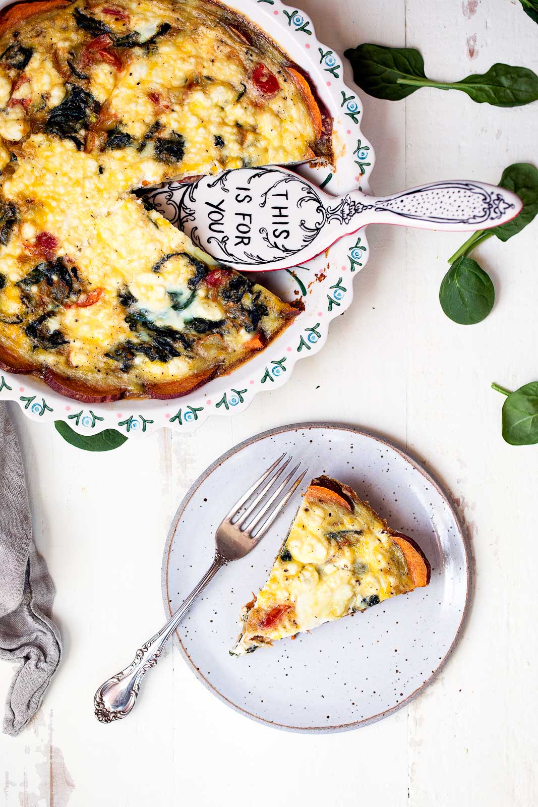 Spinach and goat cheese quiche with sweet potato crust in a pie pan and on a plate