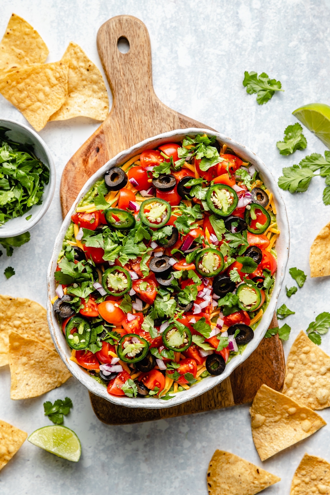 healthy 7-layer dip in a serving bowl next to tortilla chips