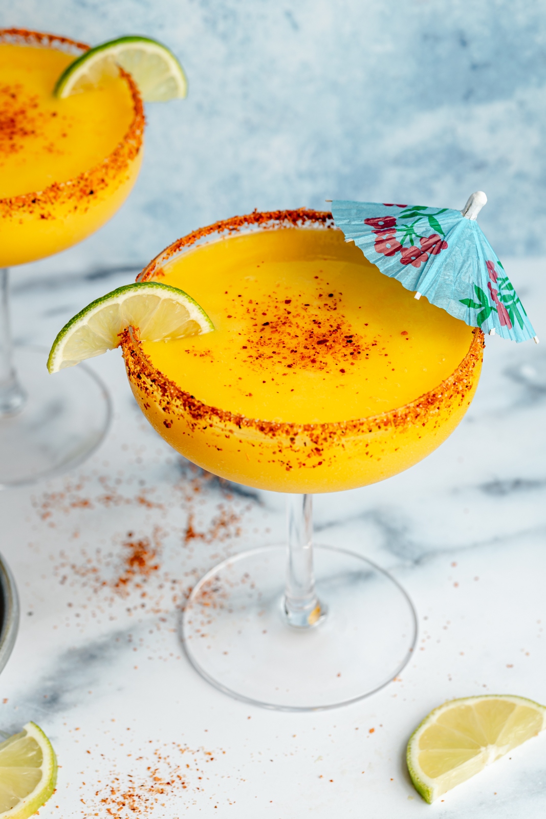 frozen mango margarita in a glass with a blue umbrella