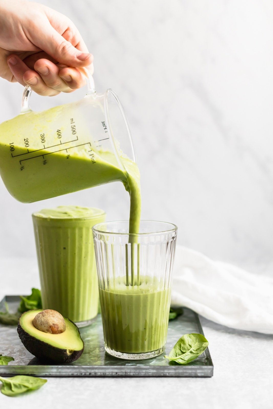 pouring a vegan green smoothie into a glass