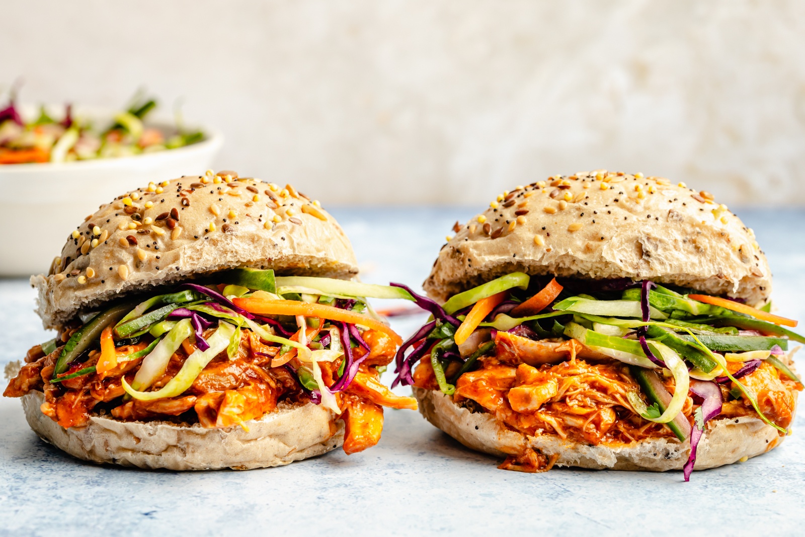 two gochujang pulled chicken sandwiches topped with slaw