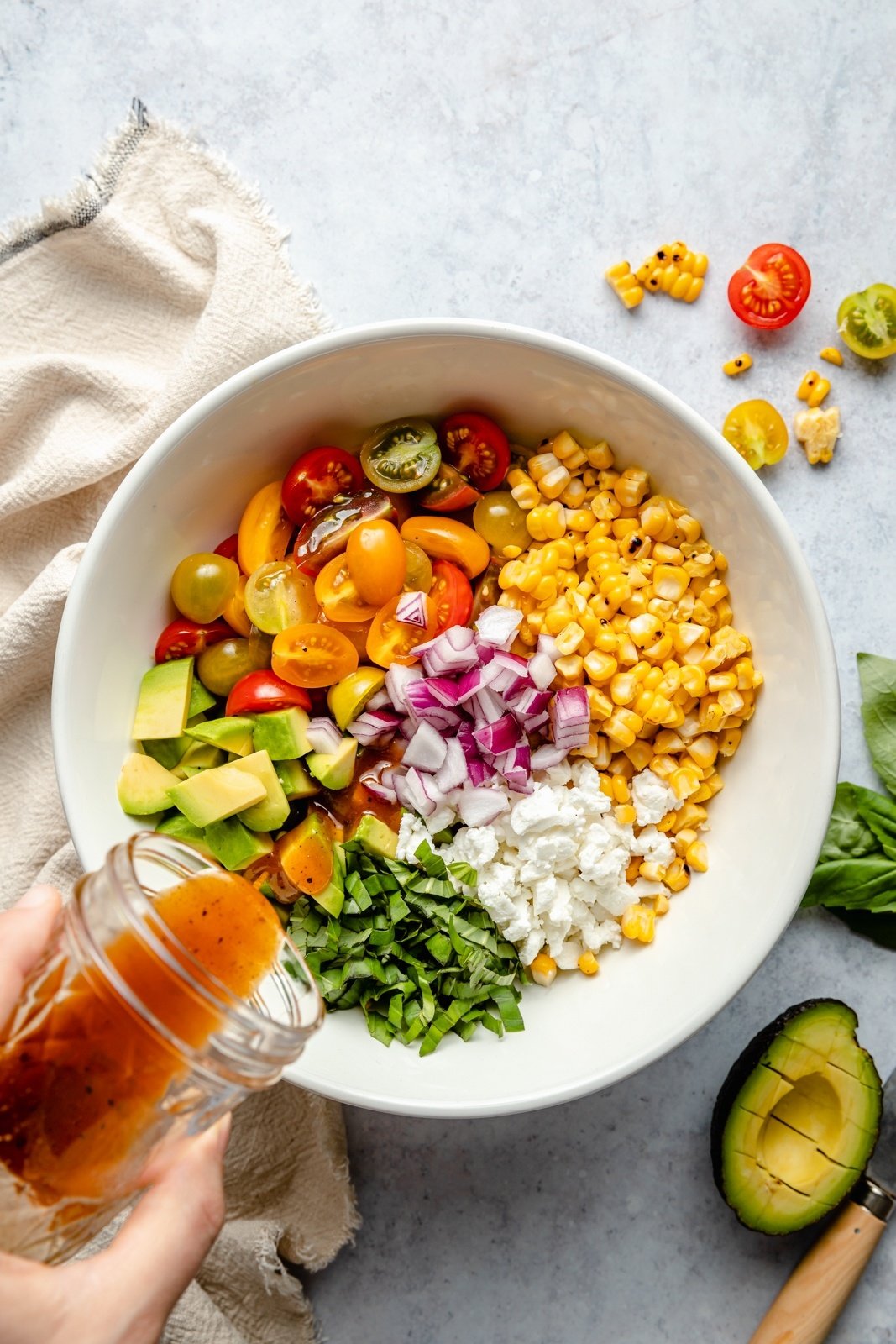 pouring hot honey vinaigrette into a bowl of grilled corn salad