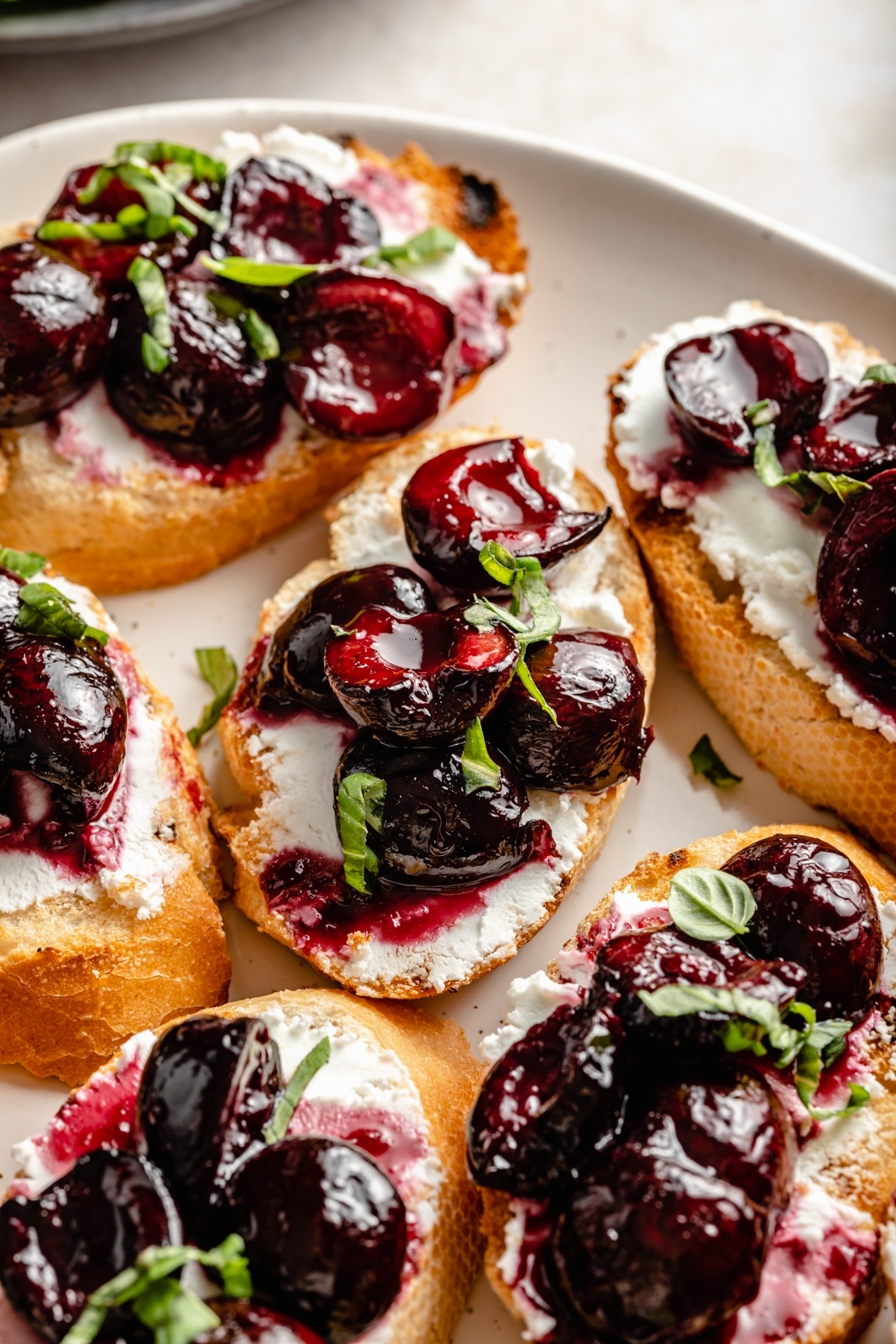 grilled crostini with roasted cherries and goat cheese on a platter