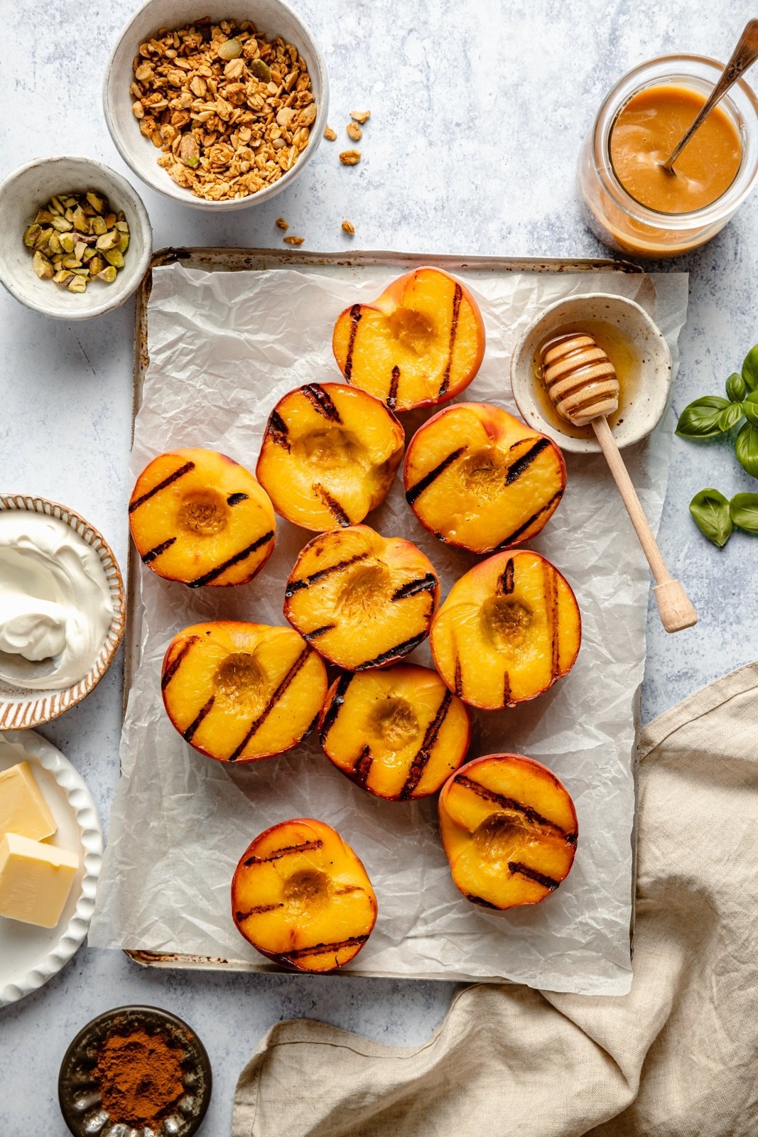 grilled peaches on parchment paper next to toppings