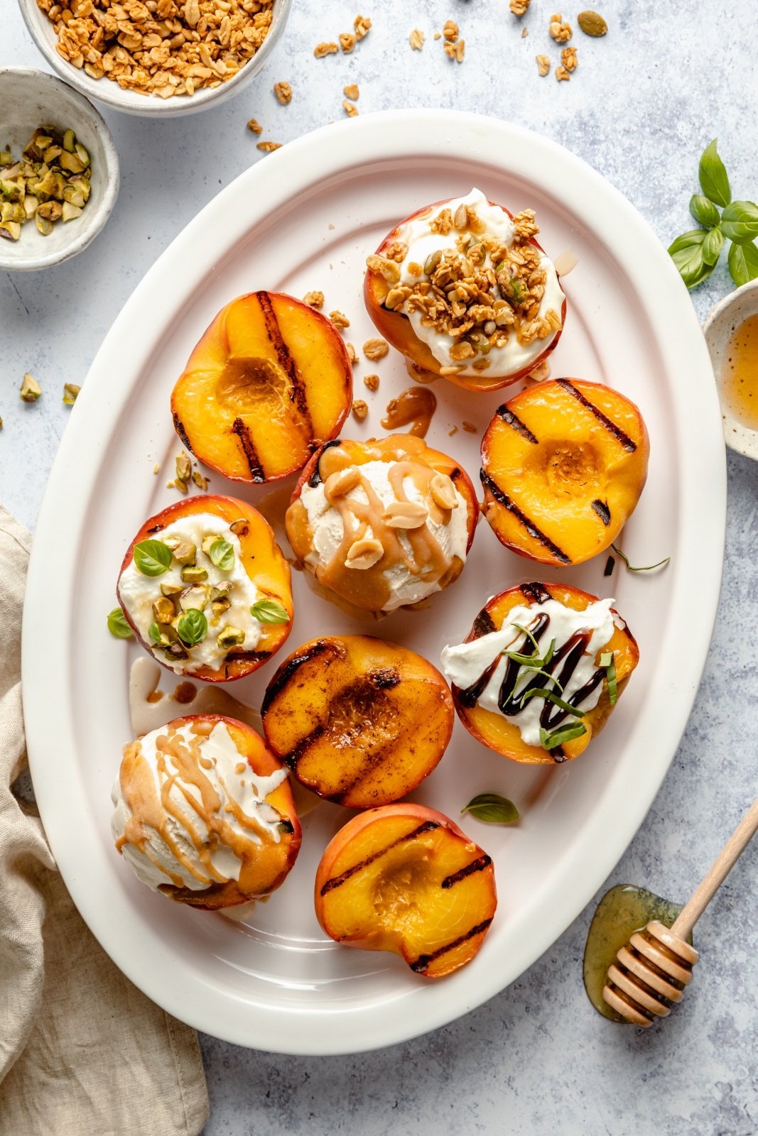 healthy grilled peaches on a platter with a variety of toppings