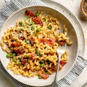 pasta carbonara with bacon and peas in a bowl