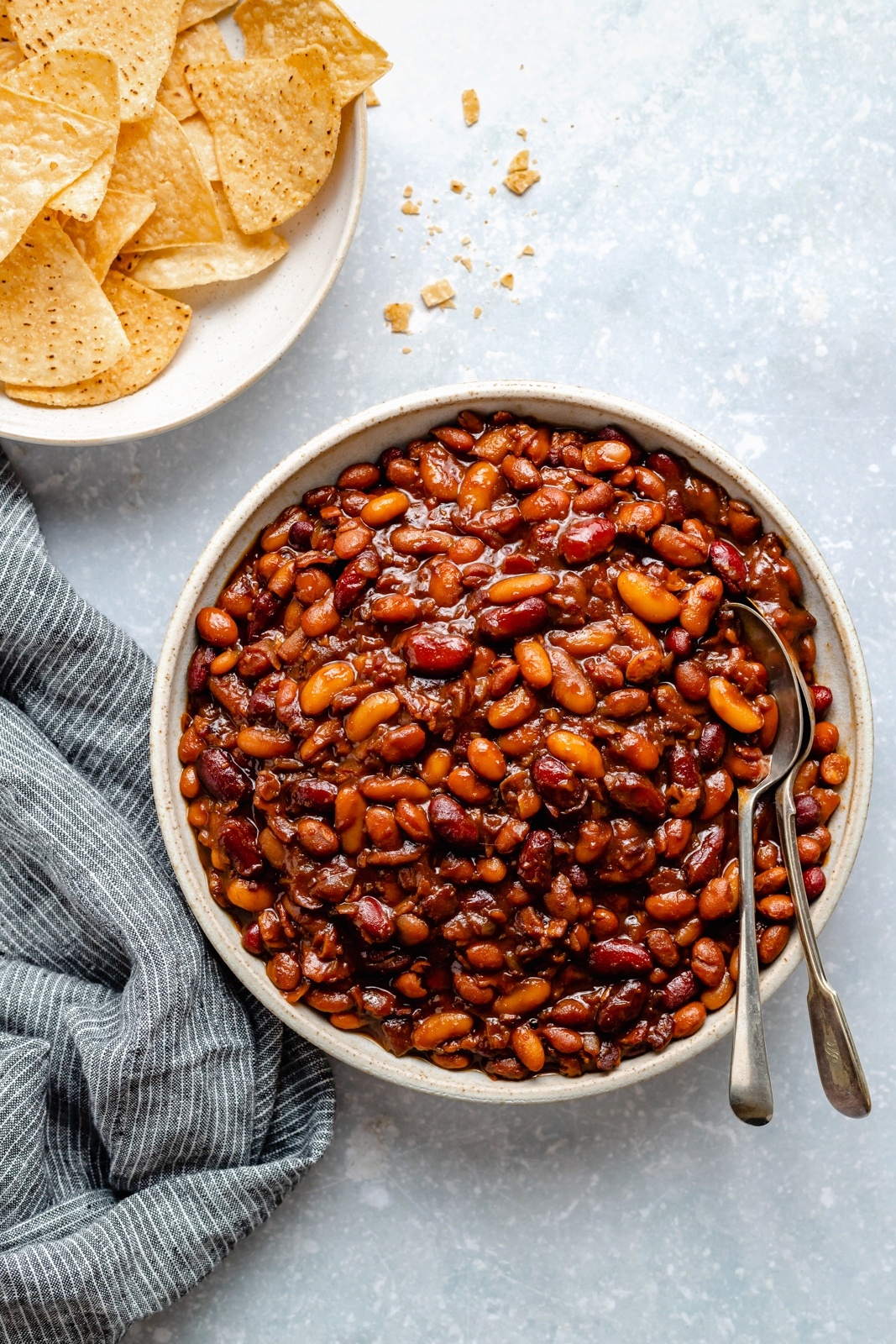 slow cooker baked beans in a bowl next to tortilla chips