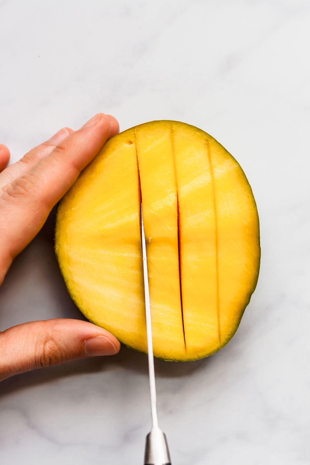 cutting half of a mango into slices