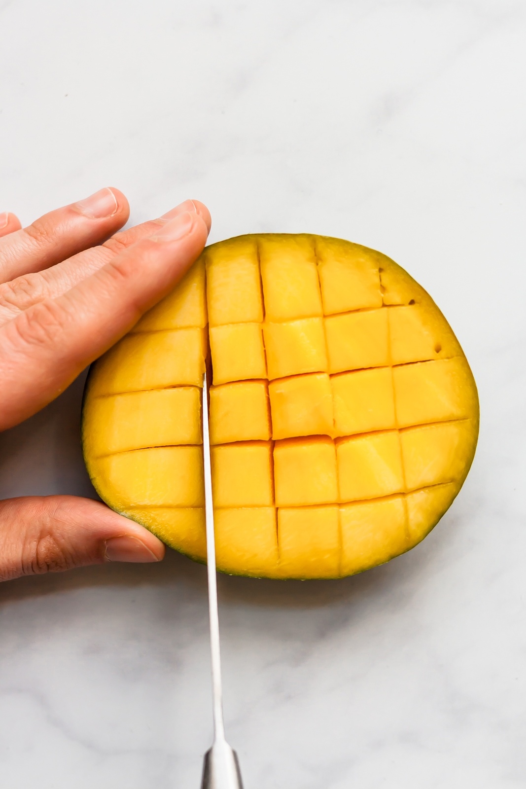 cutting half of a mango into cubes