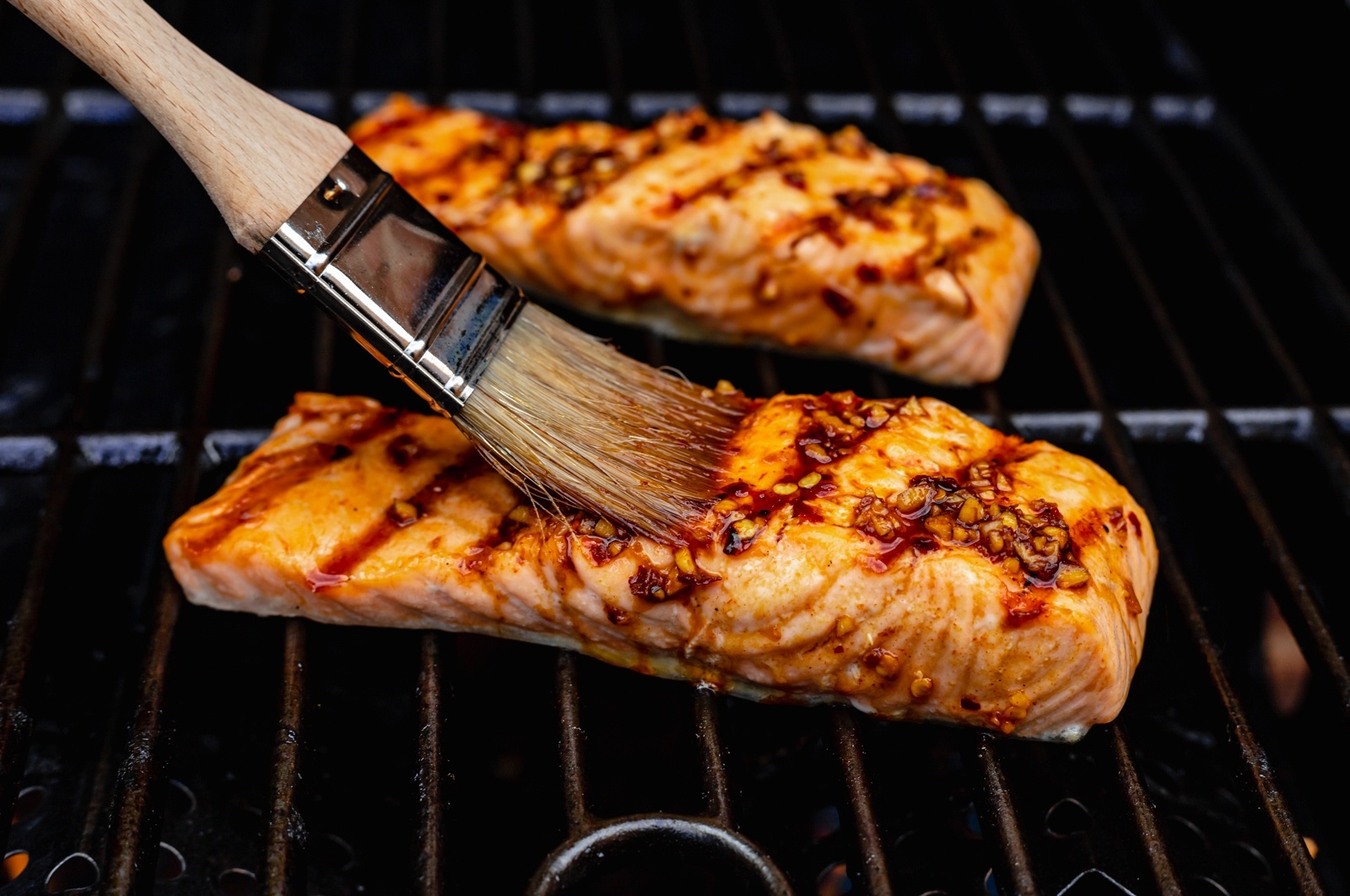 brushing salmon with a marinade on a grill