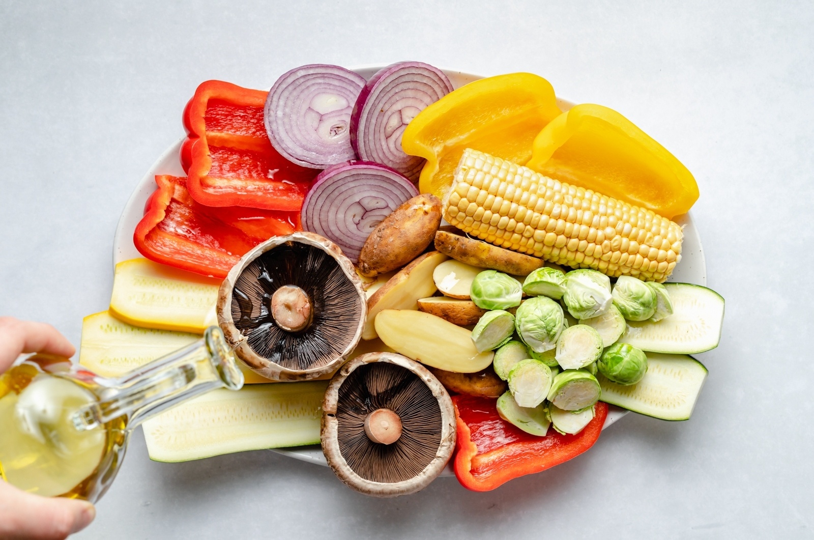 drizzling a platter of vegetables with olive oil