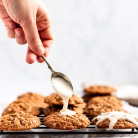 maple pecan oatmeal cookies being topped with a salted maple icing