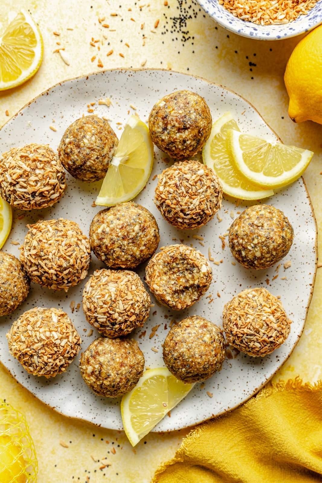 lemon poppy seed energy bites on a plate with lemon wedges