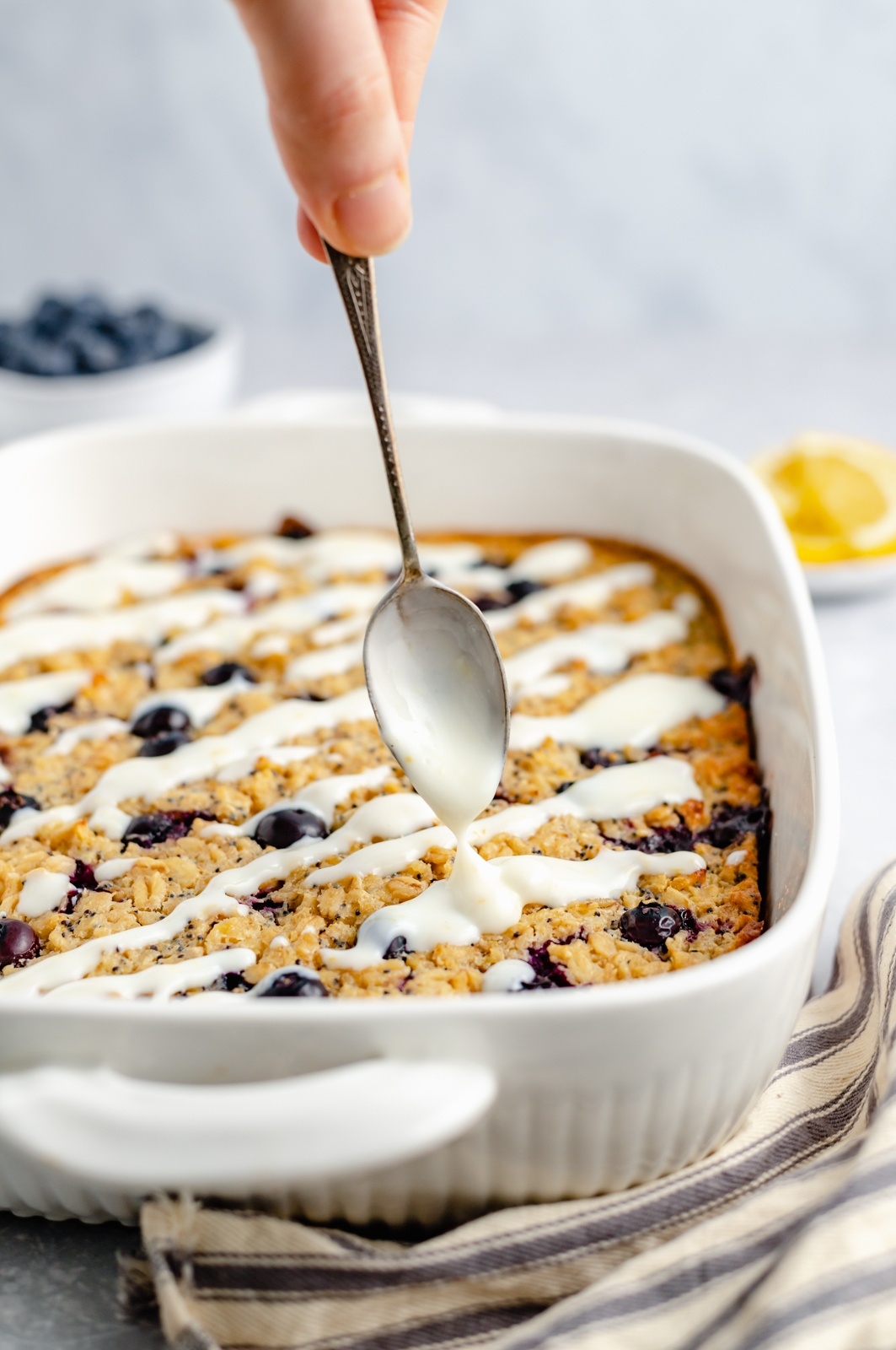 drizzling lemon glaze over a lemon blueberry oatmeal bake