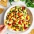 overhead shot of a chip dipping into a bowl of mango salsa