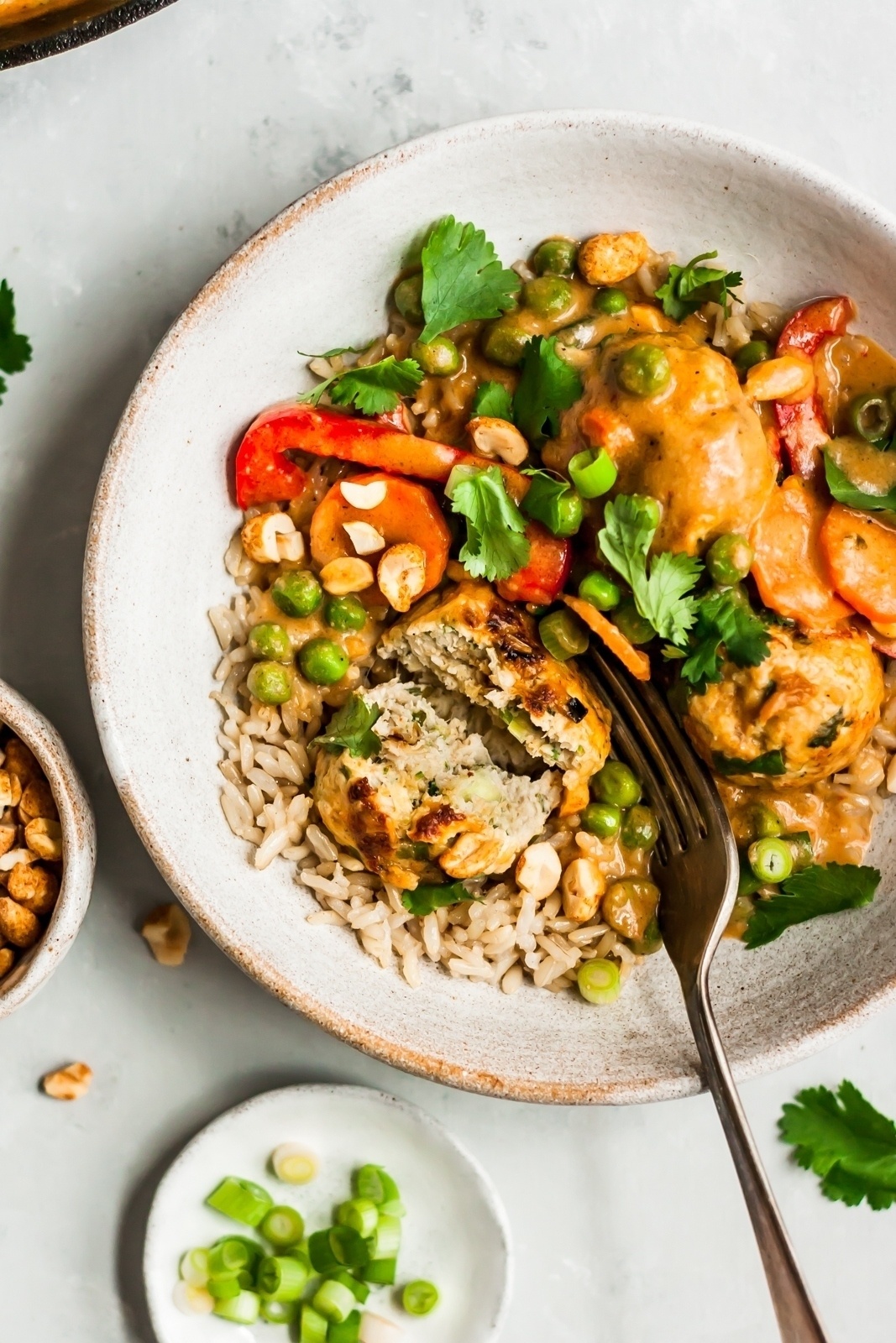 healthy ginger chicken meatballs in a bowl with veggies and rice and a fork