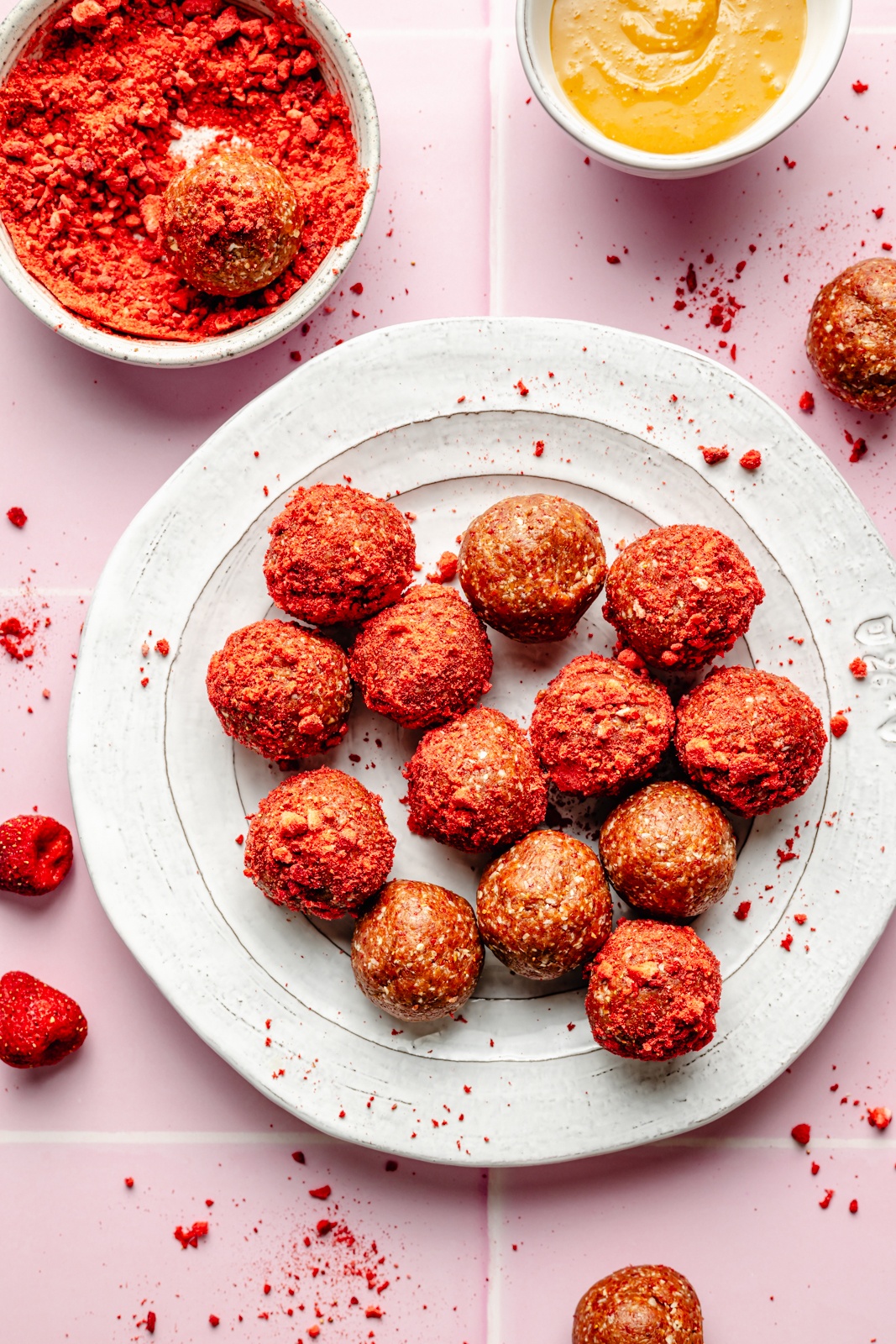 peanut butter and jelly protein bites rolled in freeze-dried strawberries on a plate