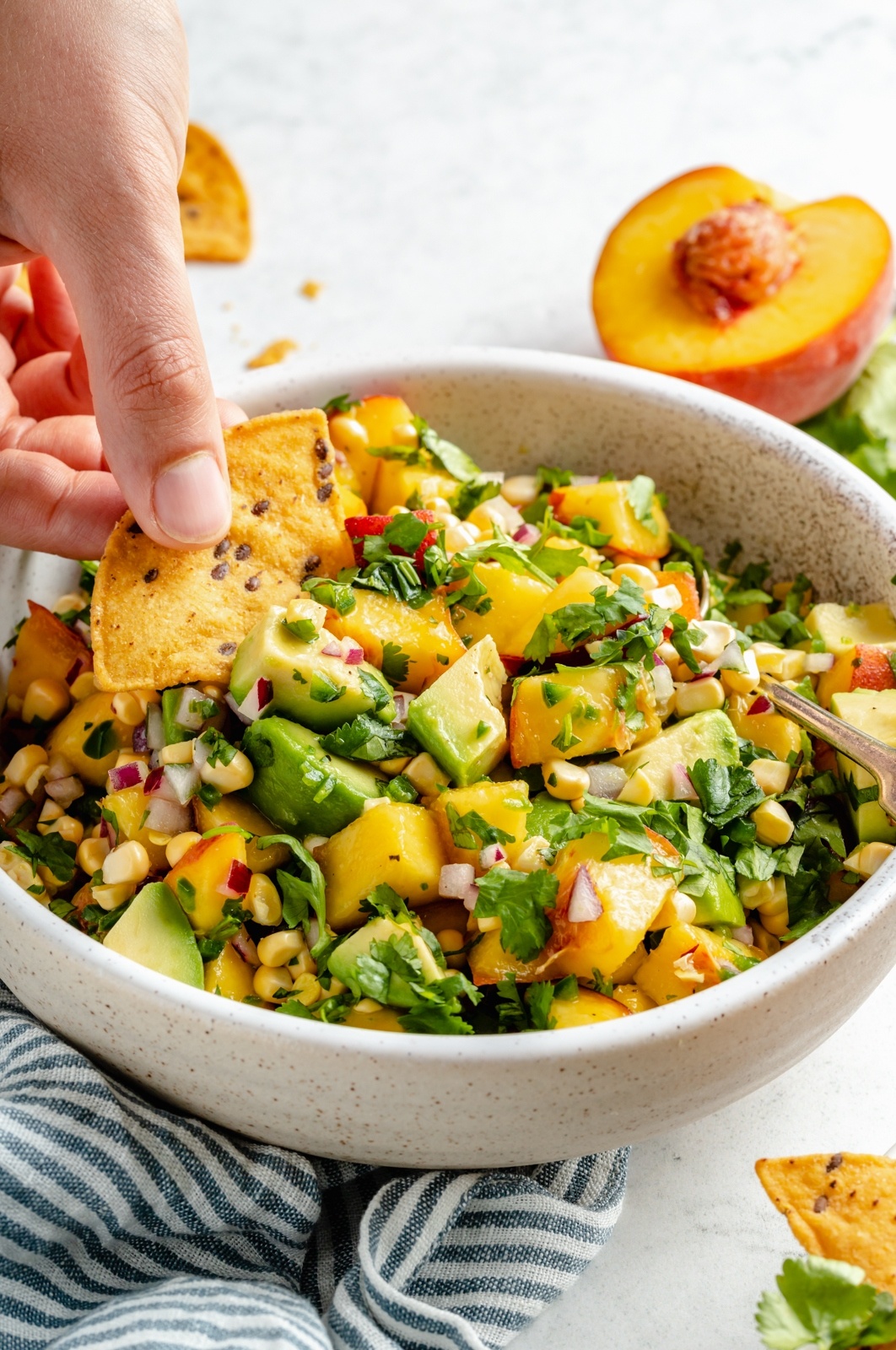 dipping a chip into avocado peach salsa