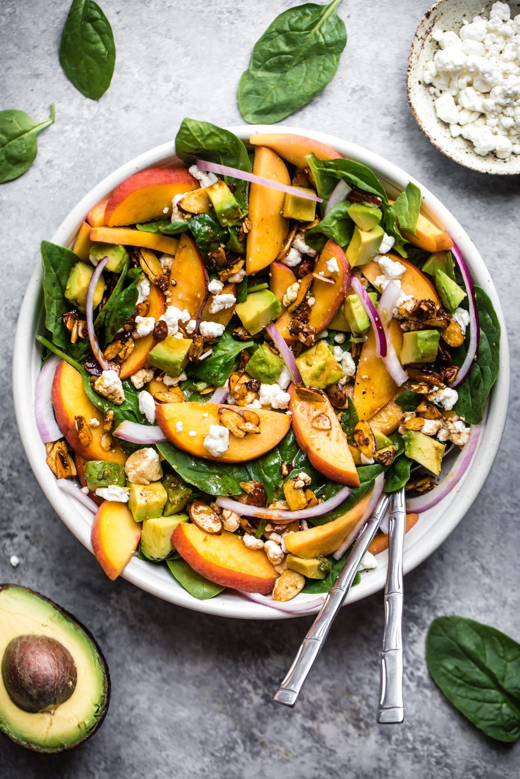 peach spinach salad with avocado and feta in a bowl