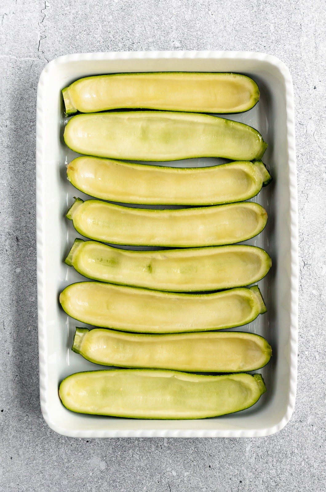 hollowed-out zucchini boats in a baking dish