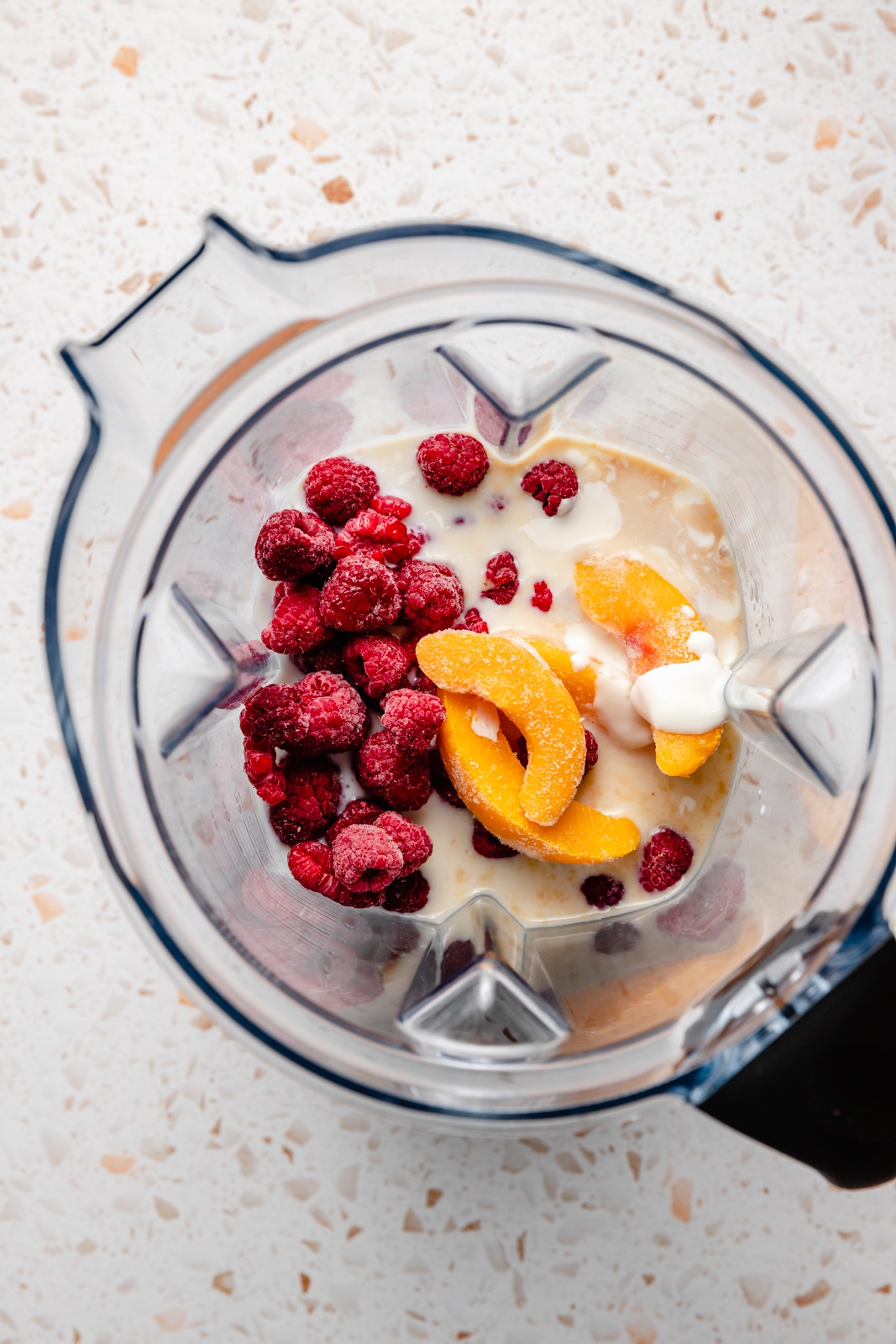 ingredients for a peach smoothie with yogurt in a blender