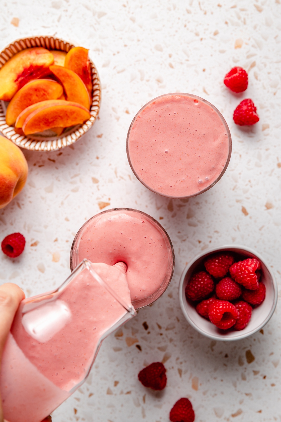 pouring a peach smoothie into a glass