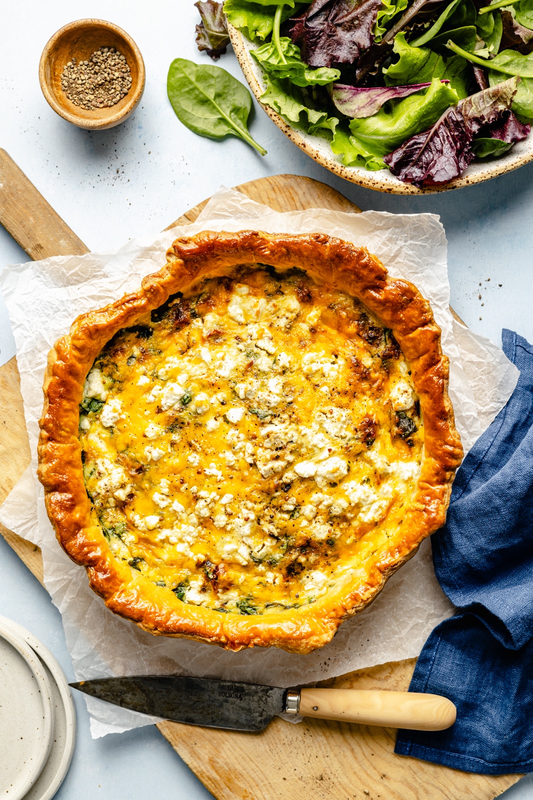 spinach and sun-dried tomato puff pastry quiche on a wooden board