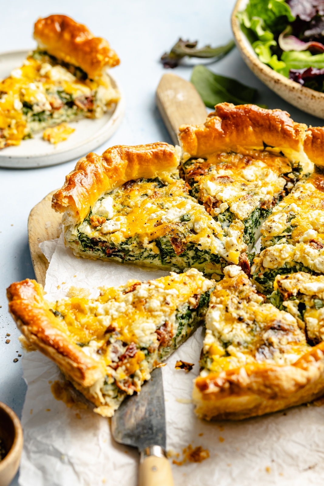 sun-dried tomato and spinach puff pastry quiche sliced on parchment paper