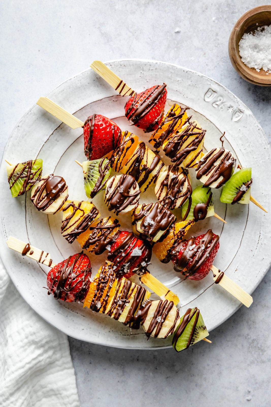 fruit skewers drizzled in chocolate on a plate