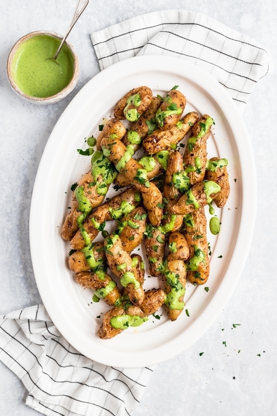 roasted garlic fingerling potatoes on a platter with green sauce