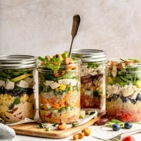 four mason jar salads next to each other