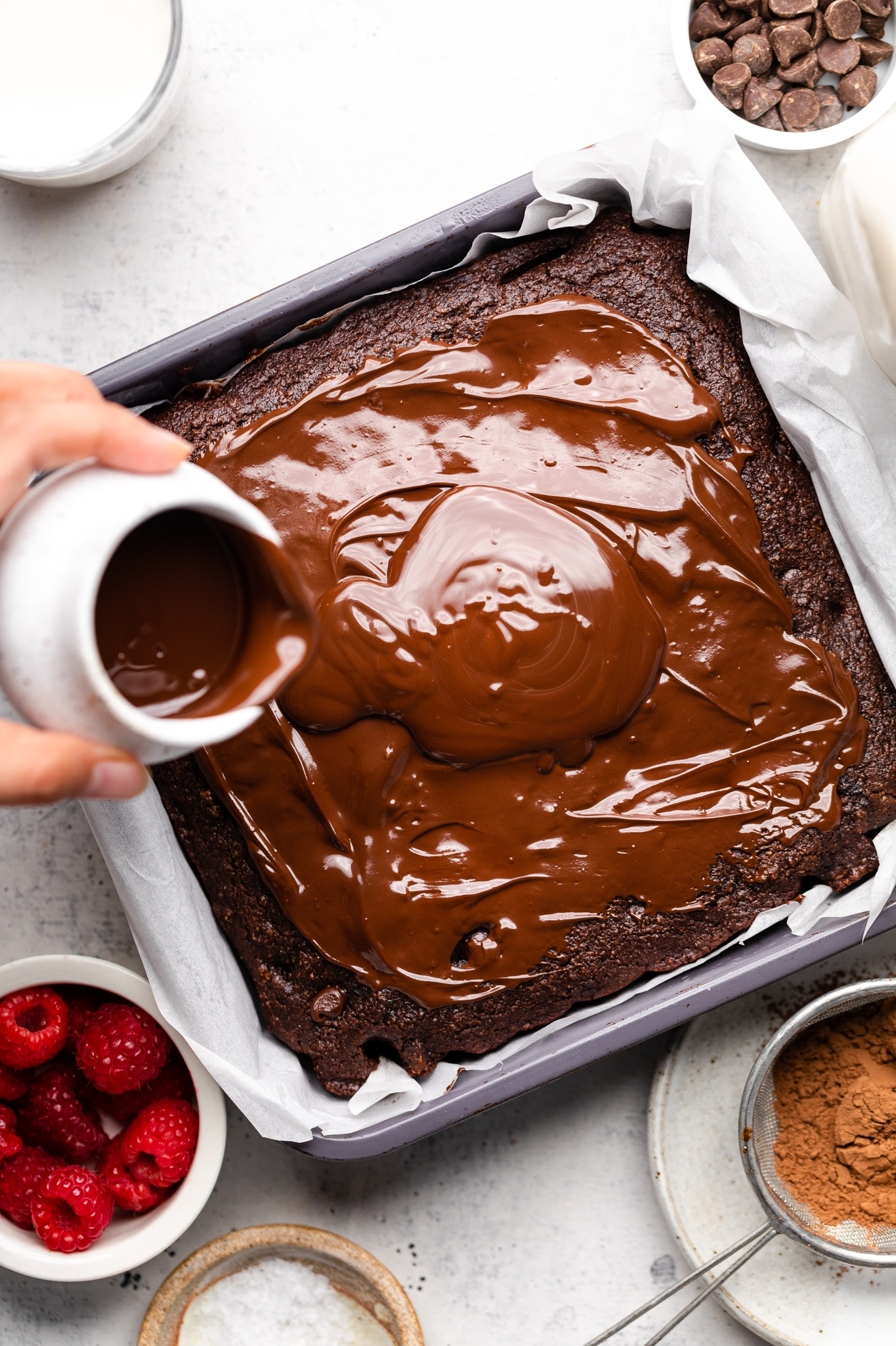 pouring chocolate frosting onto a healthy chocolate zucchini cake