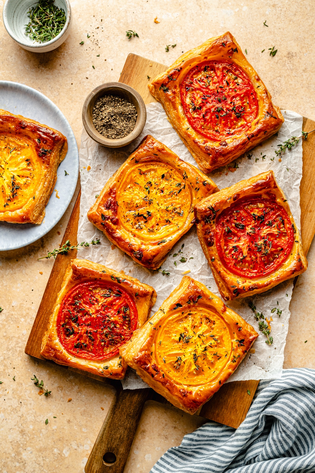 pizza tarts with tomatoes and thyme on a cutting board