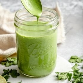 spooning cilantro yogurt sauce out of a jar