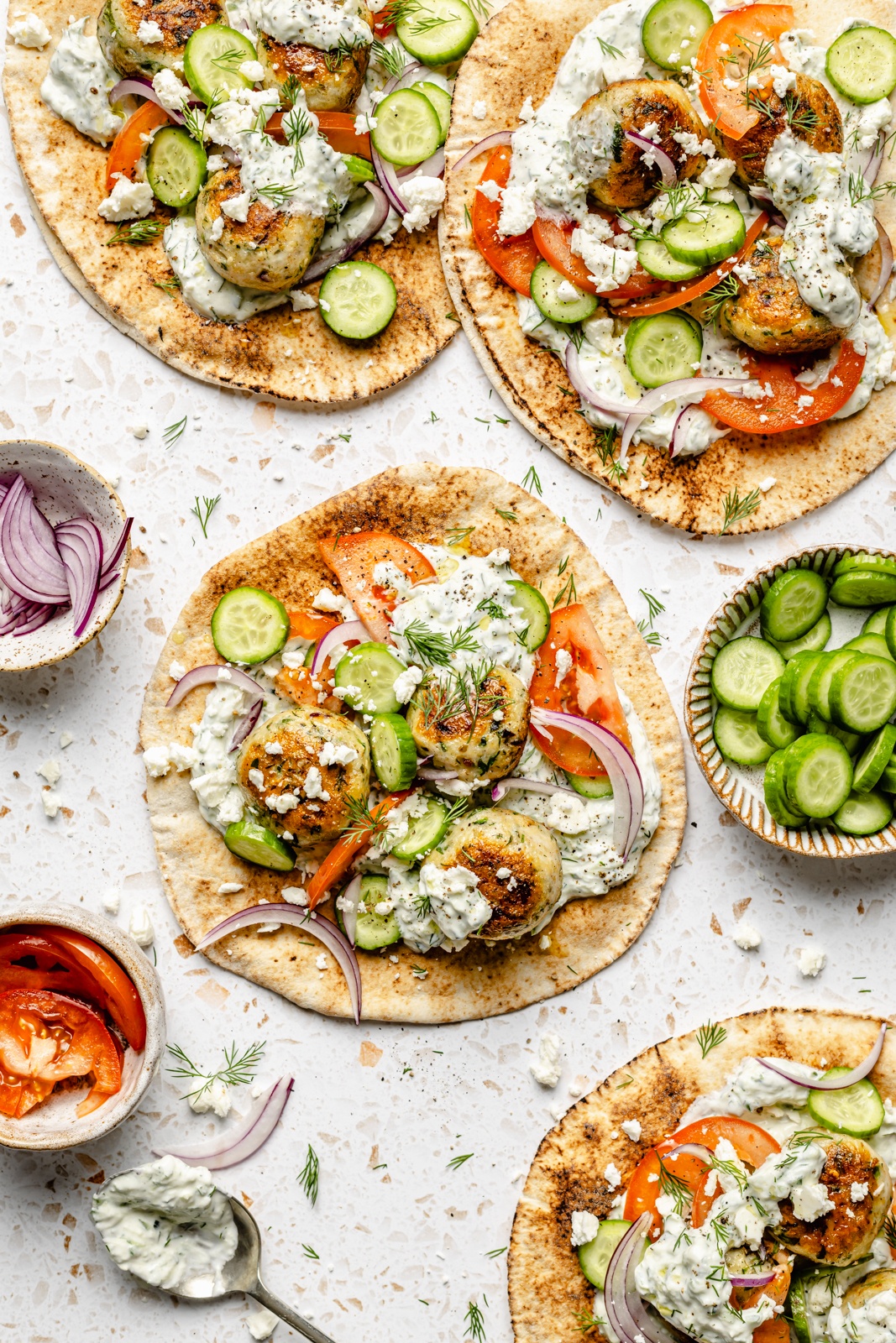 herby chicken meatball pitas topped with tzatziki, cucumber, and tomatoes