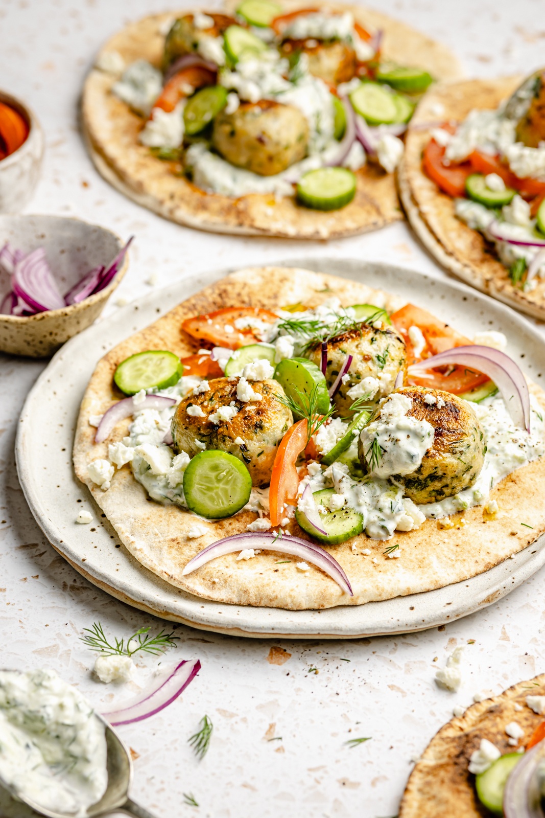 Greek chicken meatball pitas with tzatziki, cucumber, onion, and tomato