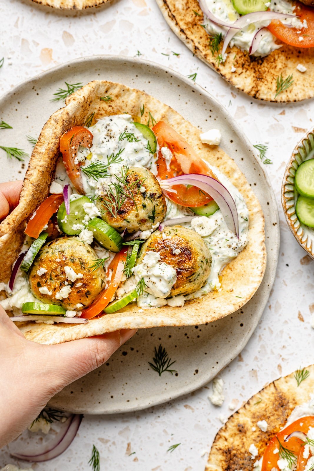 holding a chicken meatball pita sandwich