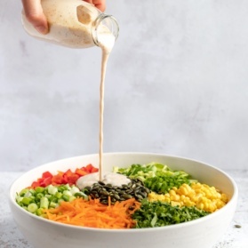 pouring homemade ranch salad dressing onto a salad