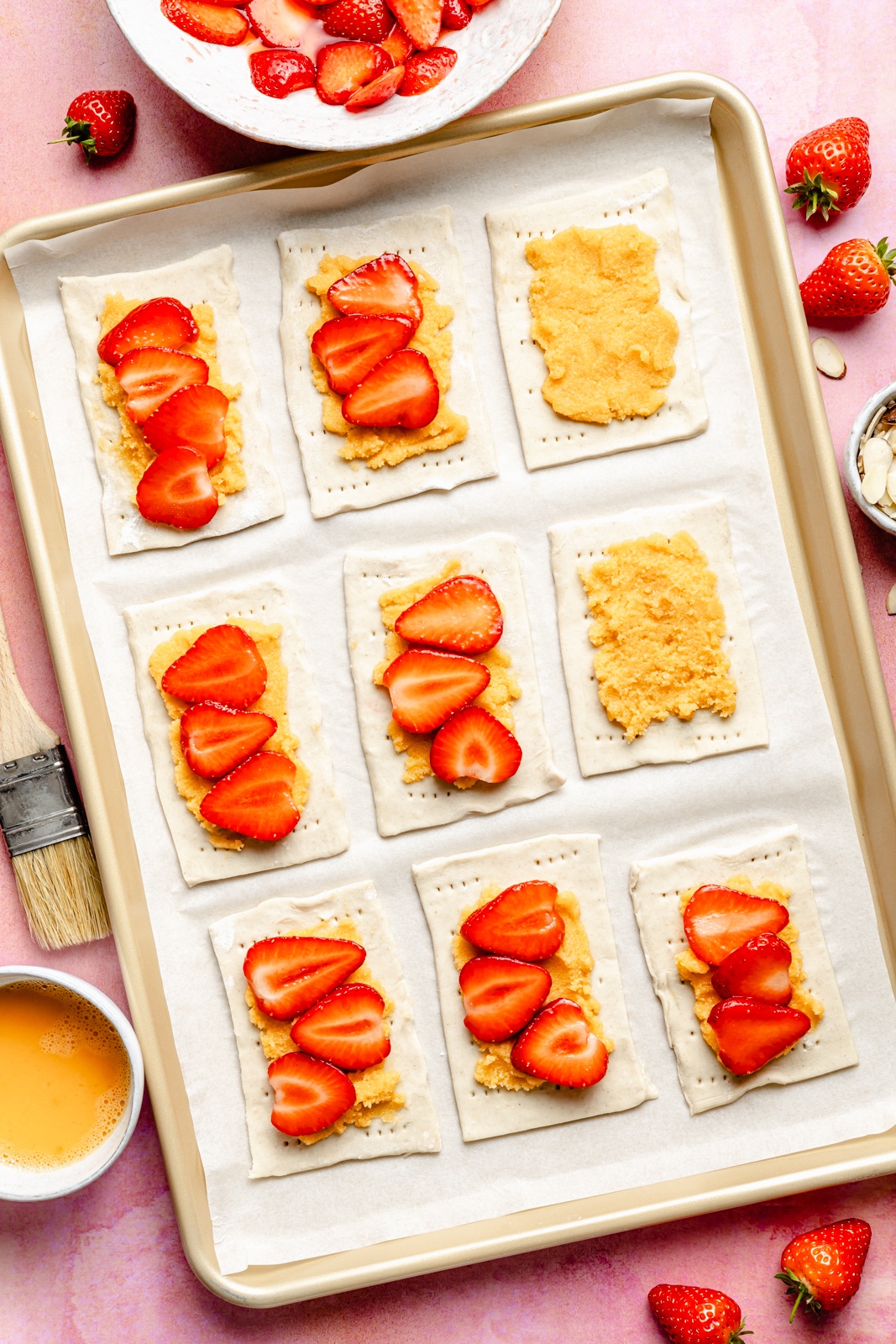 assembling strawberry almond puff pastry tarts on a baking sheet