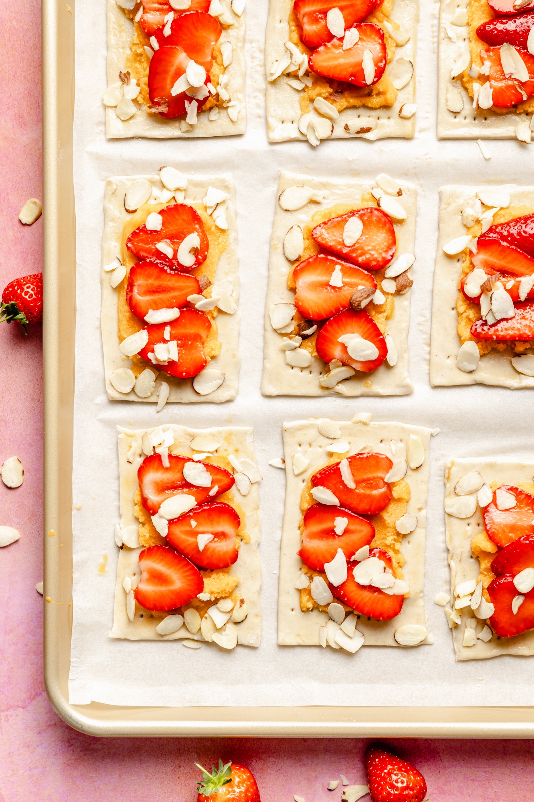 unbaked strawberry puff pastry tarts with almonds on a baking sheet