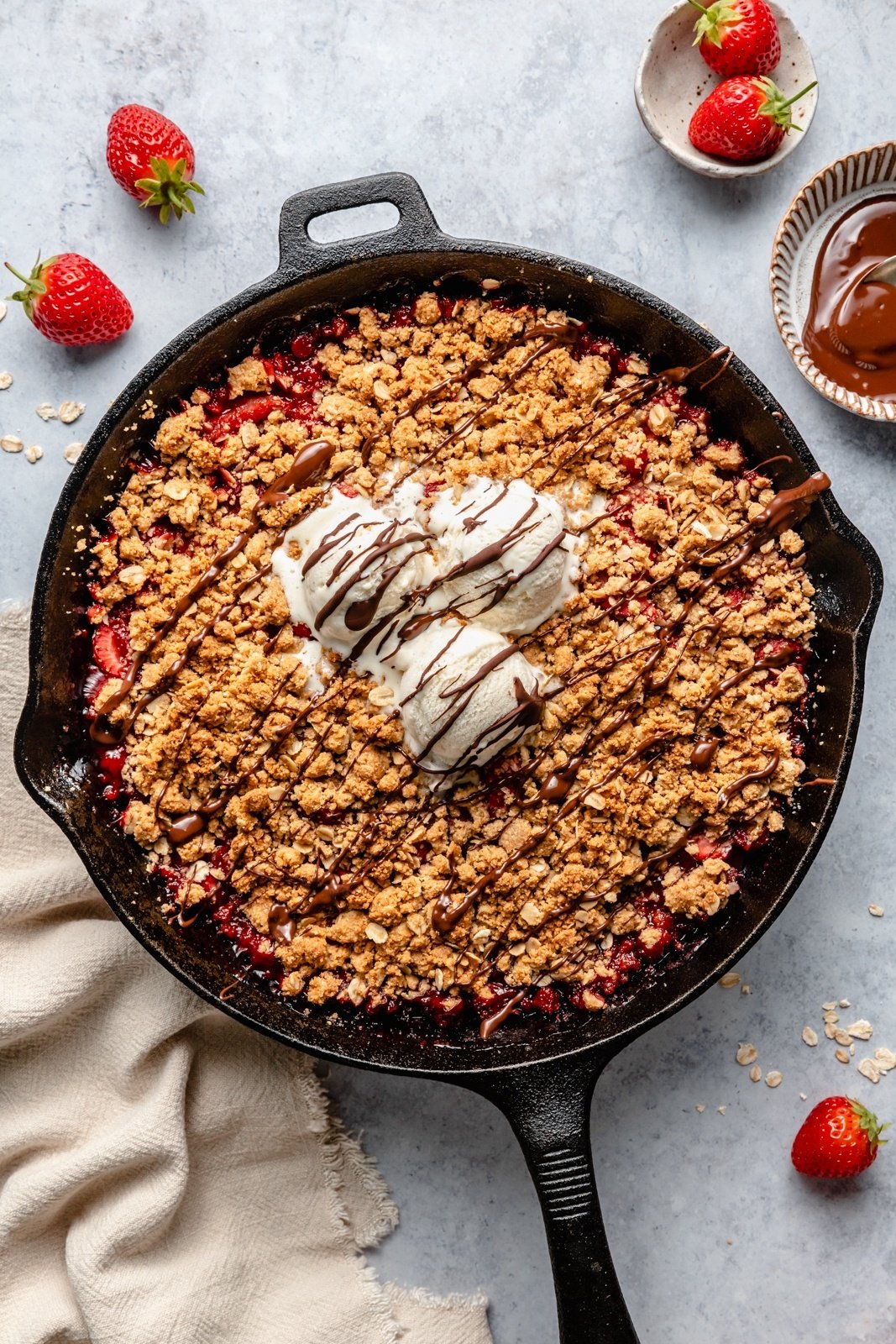 strawberry crisp in a skillet topped with ice cream