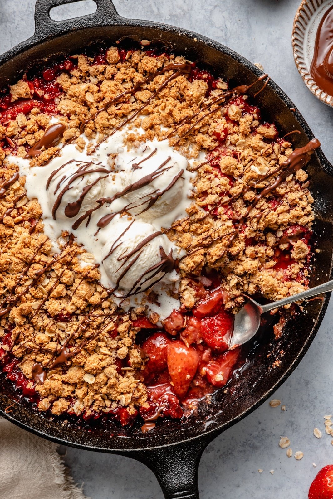 strawberry crisp in a skillet topped with ice cream