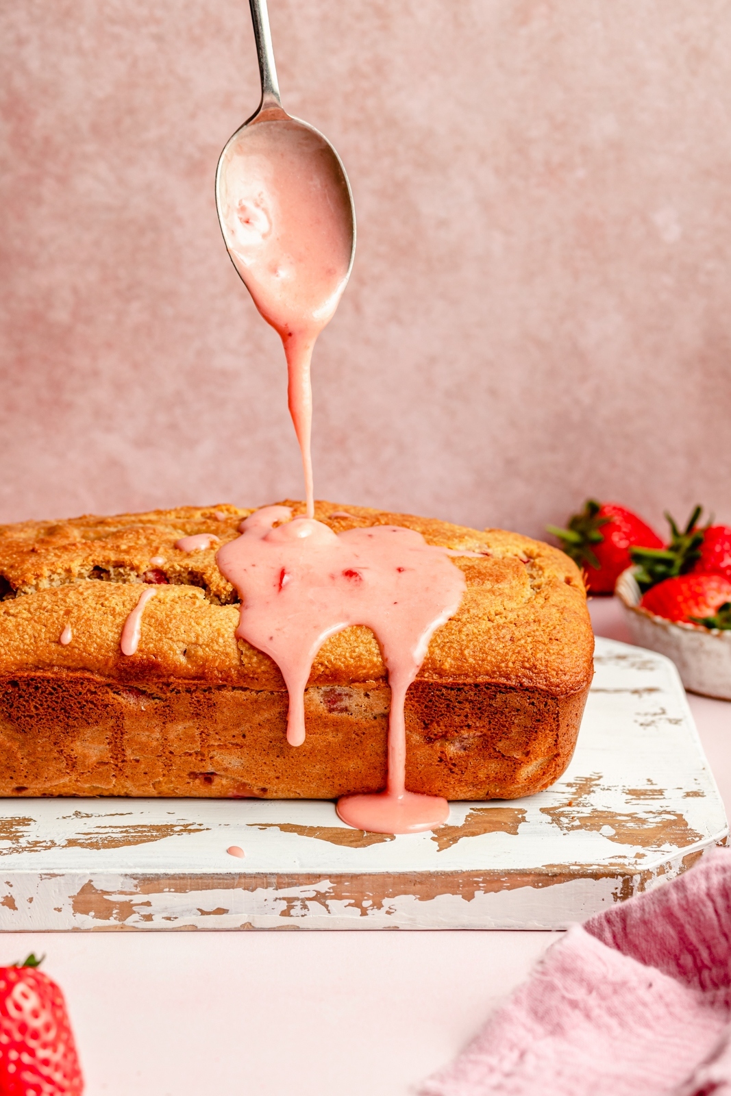 drizzling strawberry icing onto a healthy strawberry bread