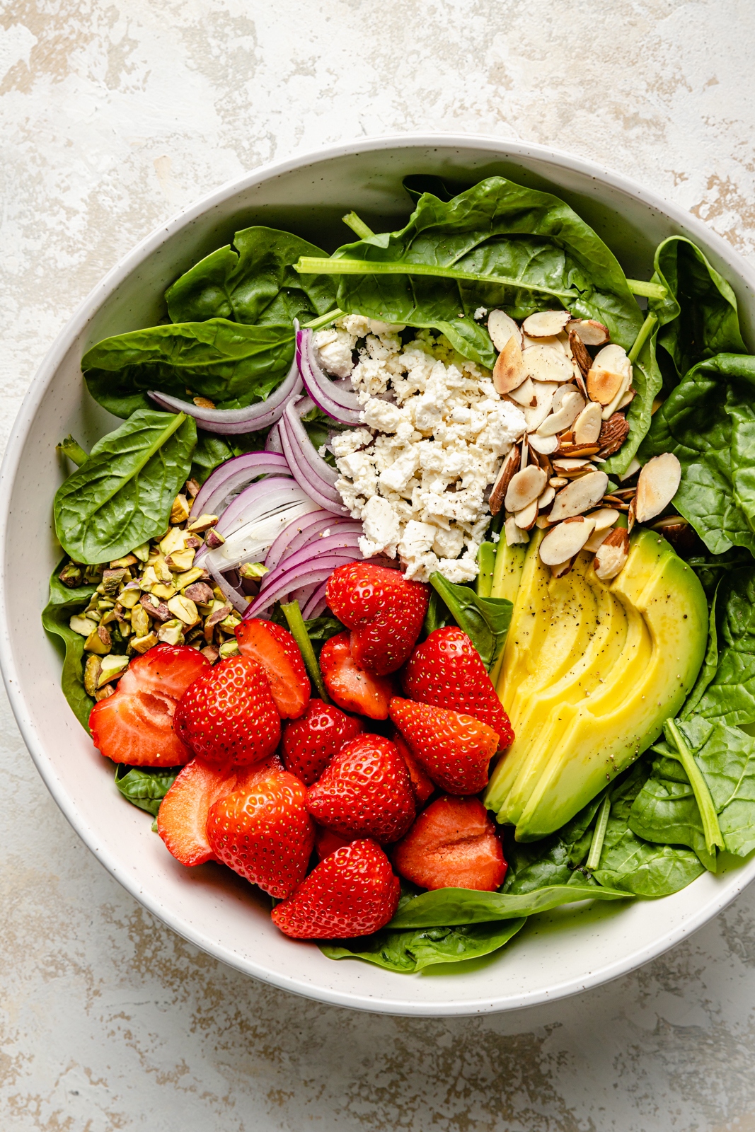 ingredients for a strawberry spinach salad in a bowl