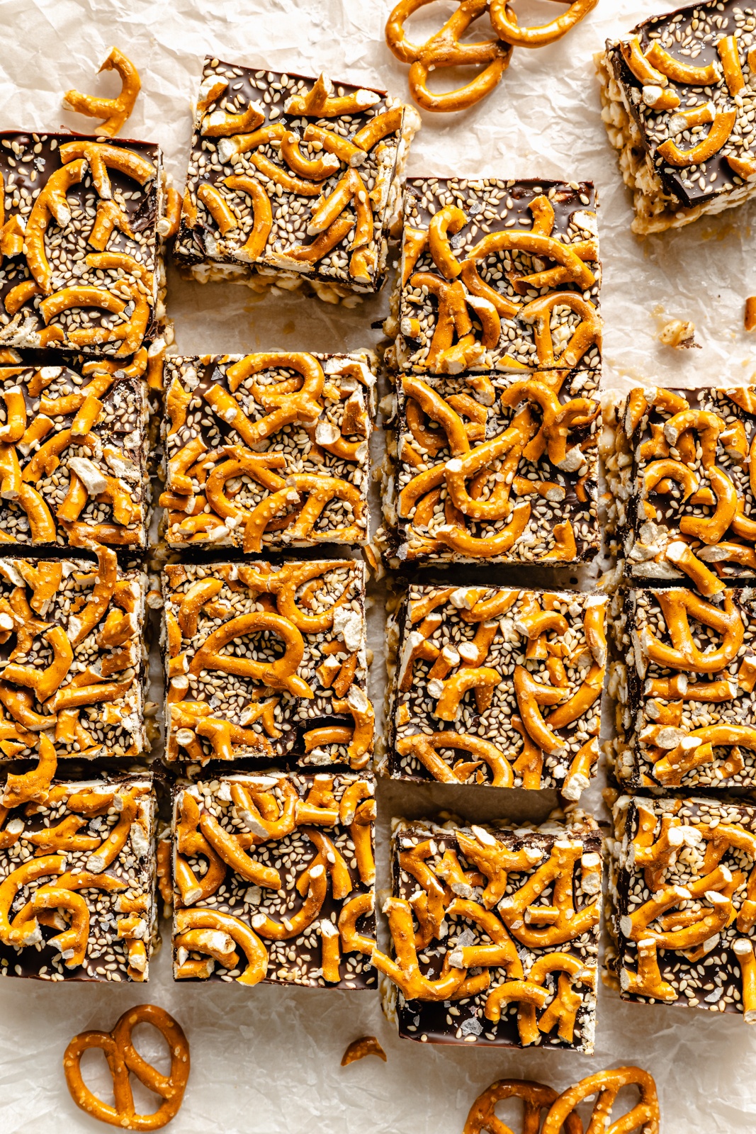 chocolate tahini rice krispie treats topped with pretzels on parchment paper